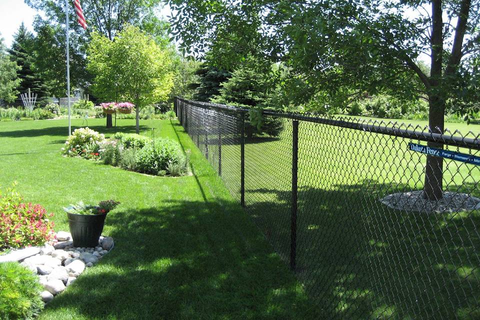 Many trees and beautiful flowers are enclosed by black PVC-coated chain link fence.