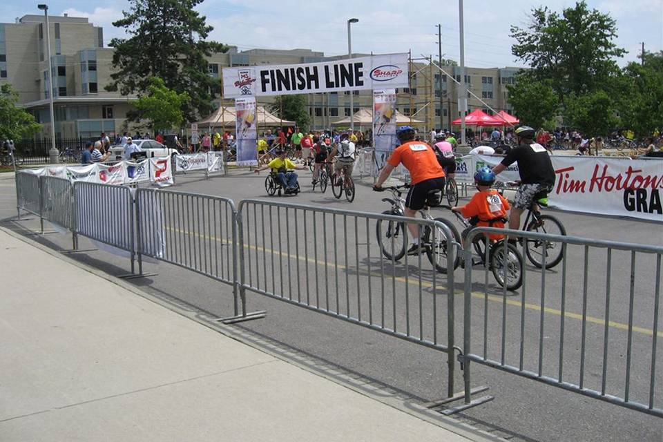 Bicycle players are riding along the bicycle race placed along the crowd control barrier.