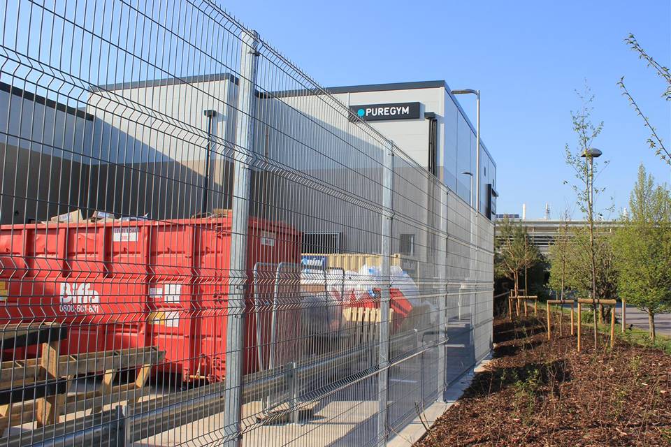 Goods are placed in a yard surrounded by curvy welded fence.