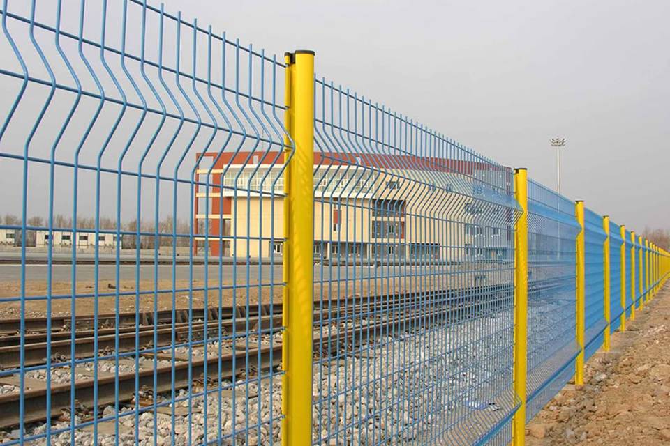 Railway tracks and an office room are encircled by curvy welded fence.