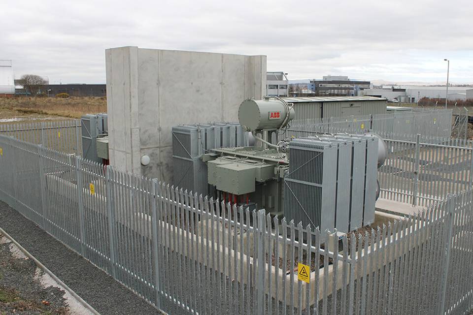 A substation is established in the open air and enclosed by palisade fencing.