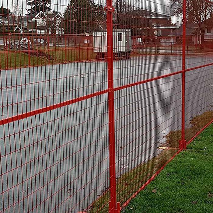 Red Canada temporary fence is set between the lawn and the road.